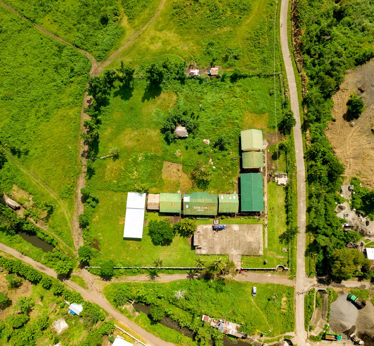 Aerial shot showcasing rural farmland with buildings, roads, and greenery.
