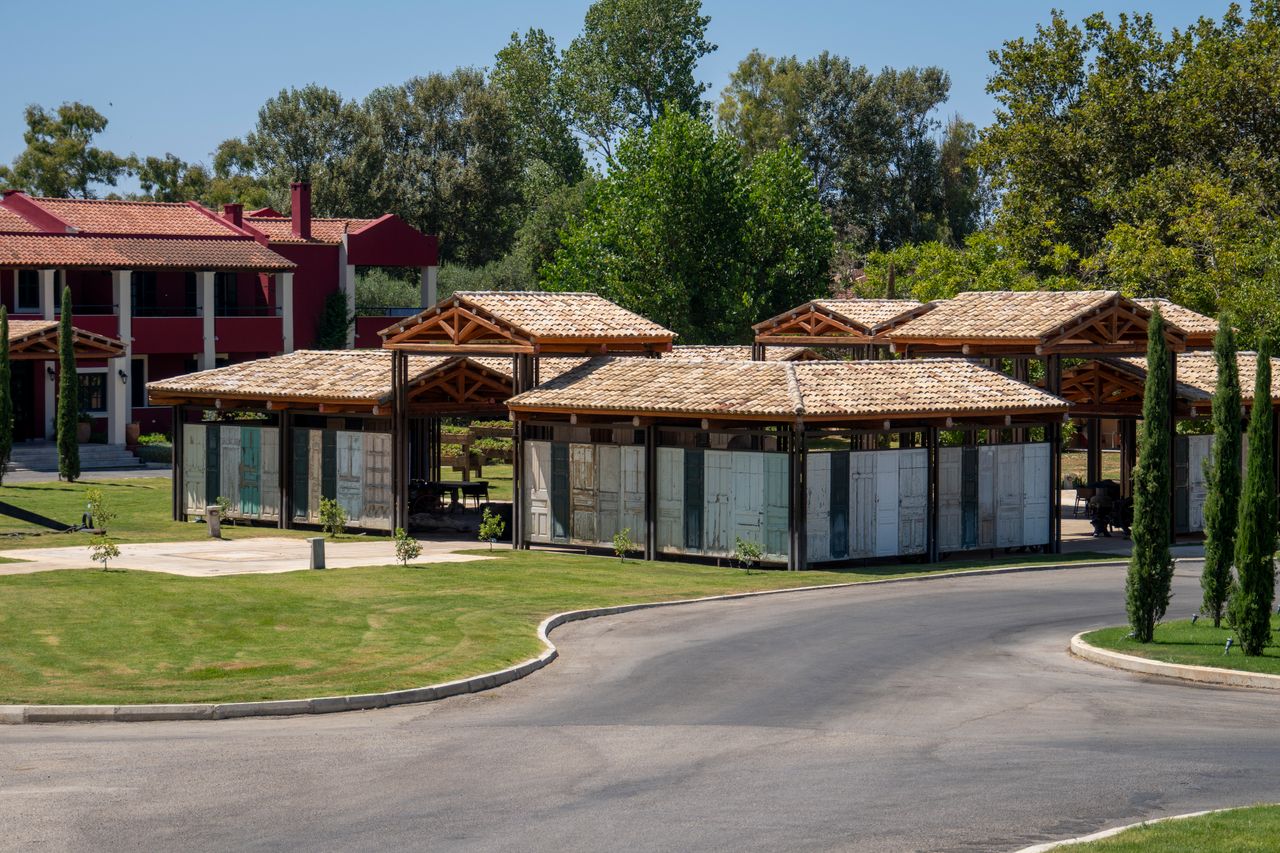 Beautiful wooden pergolas in a lush garden setting of a Corfu resort, perfect for relaxation.