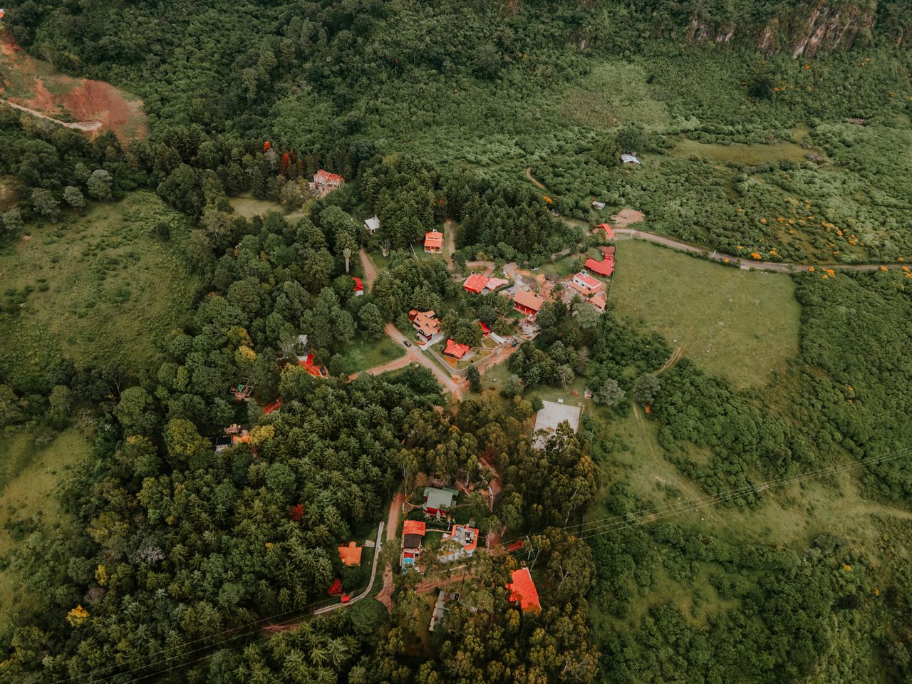 A picturesque aerial view of a countryside with red rooftops surrounded by lush greenery and trees.