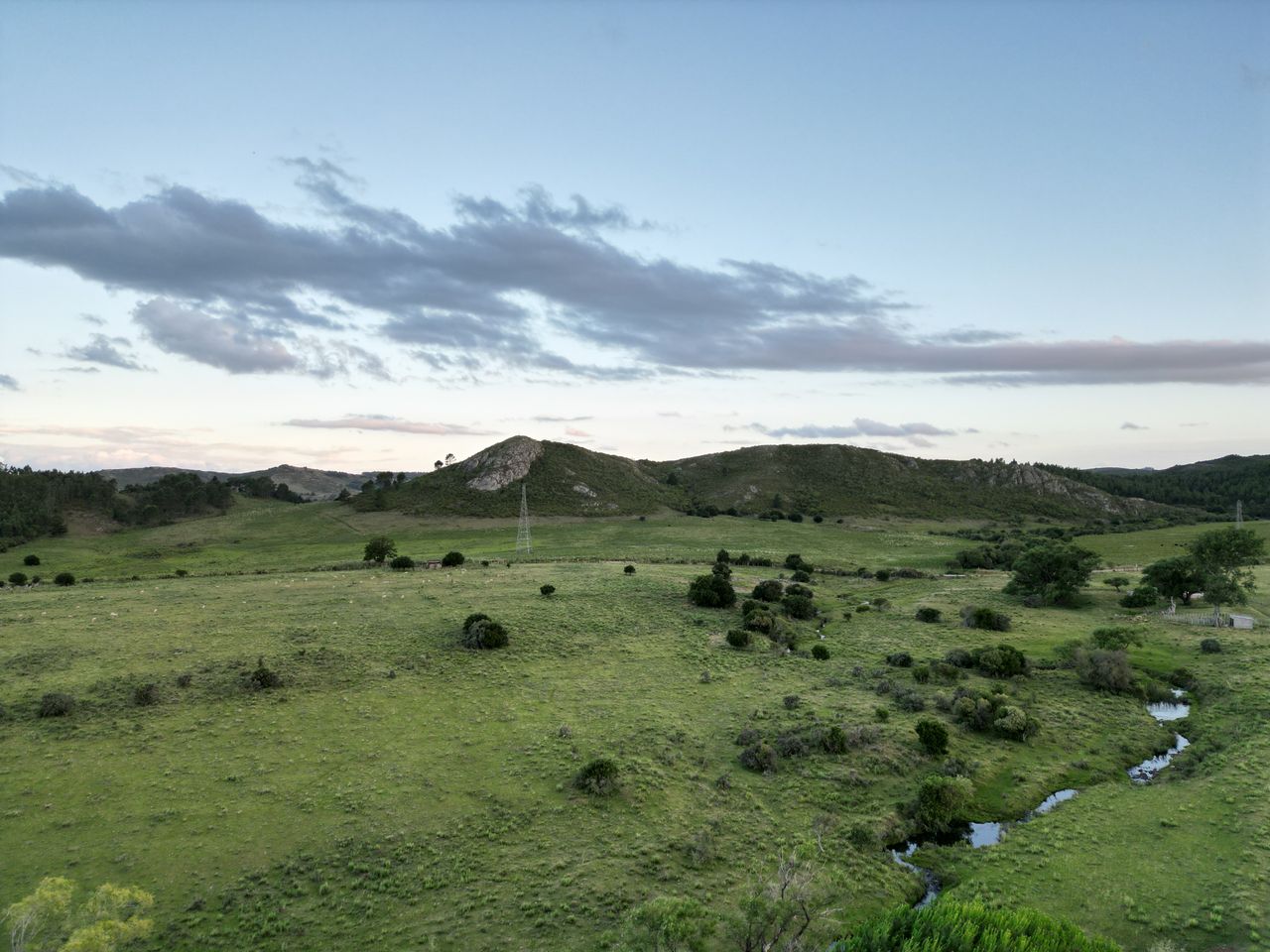 A serene landscape featuring rolling green hills, pastures, and a clear sky at dusk, ideal for nature lovers.
